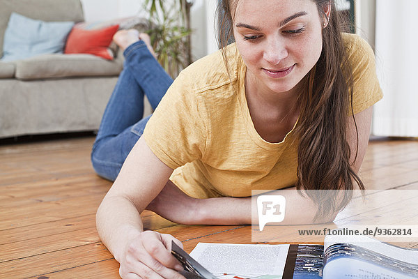 Porträt einer jungen Frau beim Lesen eines Magazins zu Hause