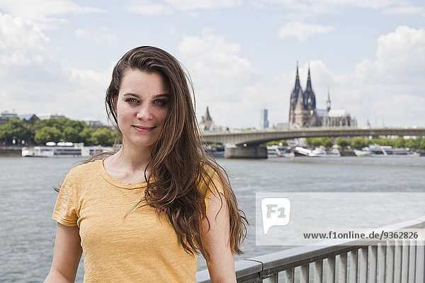 Germany  Cologne  portrait of smiling young woman standing in front of Rhine Rive
