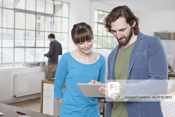 Zwei Kollegen in einem Kreativbüro mit digitalem Tablett