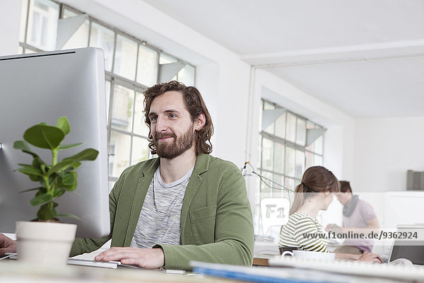 Portrait of young man working at computer in a creative office