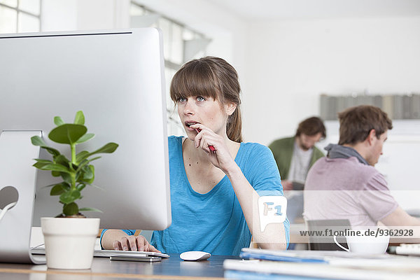 Portrait of young woman working at computer in a creative office