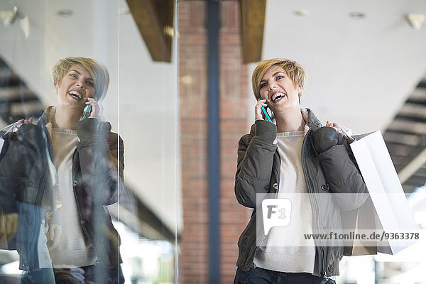 Portrait of laughing woman telephoning in front of a window display