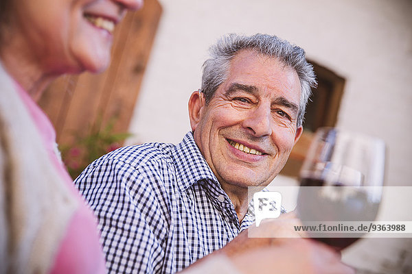 Deutschland  Nordrhein-Westfalen  Bornheim  Seniorenpaar im Hof sitzend  Rotwein trinkend