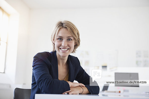 Portrait of smiling young woman at her desk in a creative office