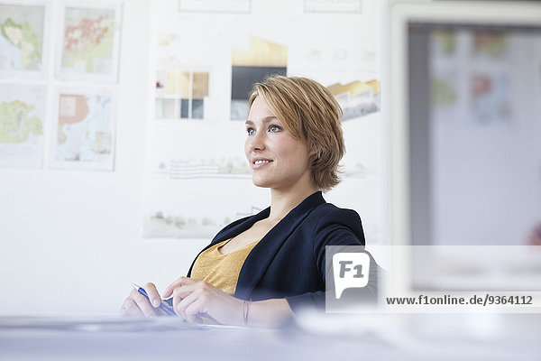 Portrait of smiling young woman at her desk in a creative office