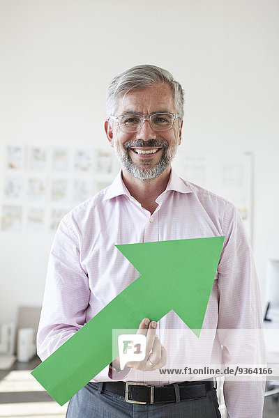 Porträt eines lächelnden Geschäftsmannes mit grünem Pfeil