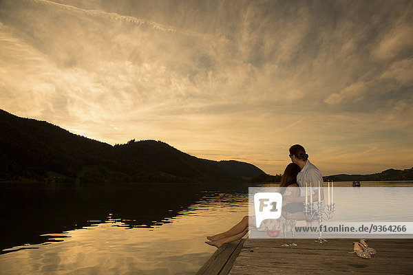 Germany  Bavaria  couple watching sunset from a jetty at Schliersee by evening twilight