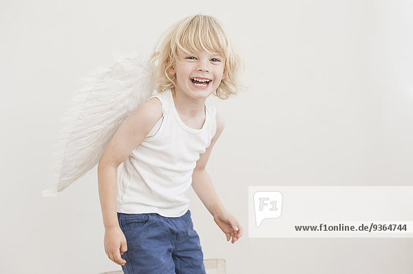 Portrait of laughing little boy with angle wings