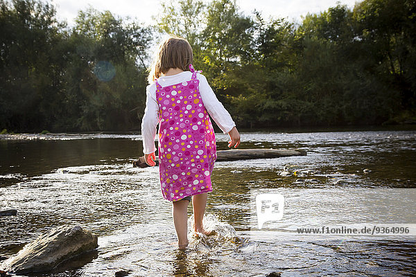 Kleines Mädchen spielt am Flussufer