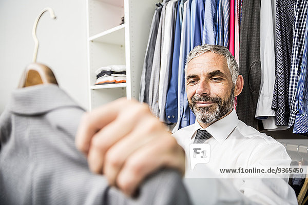 Portrait of businessman choosing jacket at his walk-in closet
