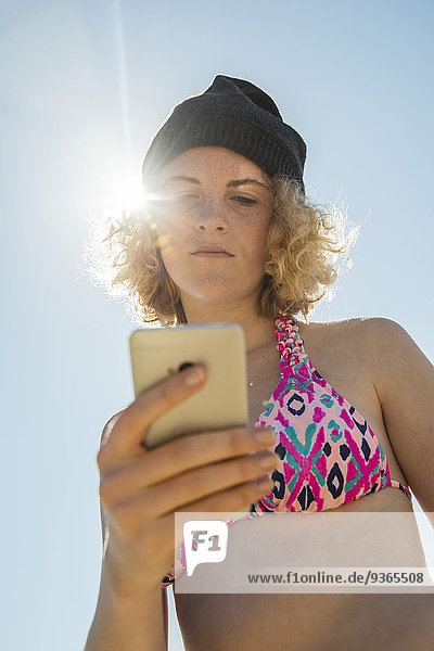 Teenager Mädchen mit ihrem Smartphone am Strand