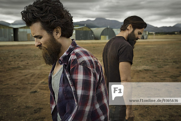 Two men with full beards in abandoned landscape