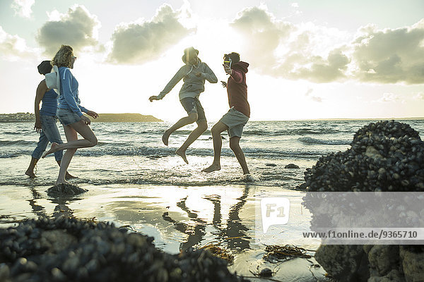Frau und drei Teenager am Strand bei Sonnenuntergang