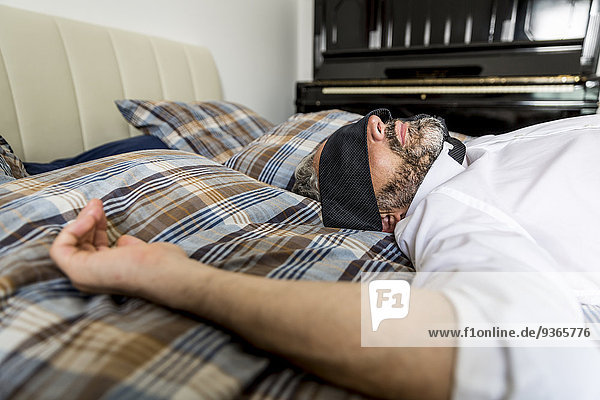 Businessman lying on his bed with tie covering his eyes