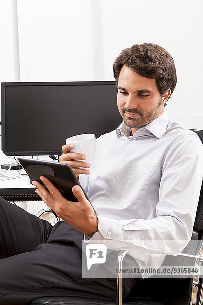 Junger Geschäftsmann mit Tablet-Computer in seinem Büro