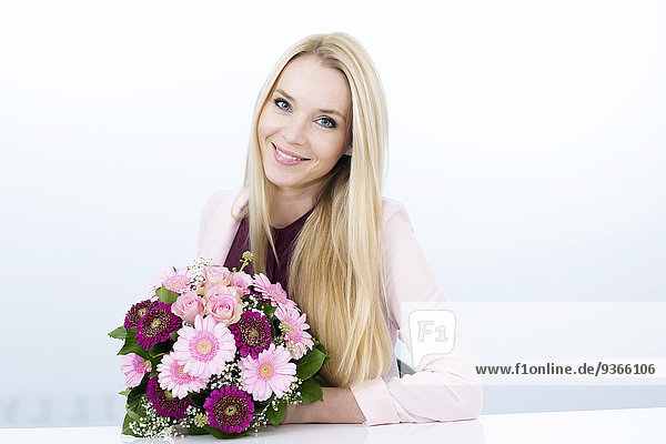 Porträt einer lächelnden jungen Frau mit Blumenstrauß