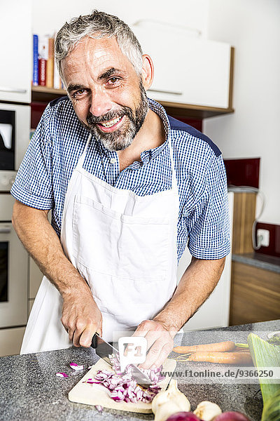 Österreich  Mann in der Küche beim Zwiebelschneiden