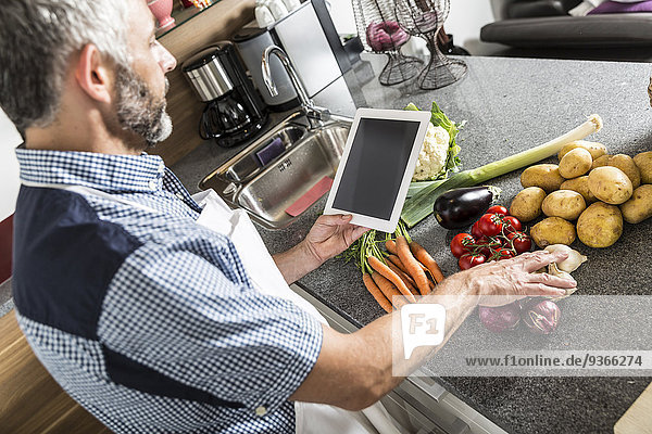 Österreich Mann in der Küche mit digitaler Tablette zur Zubereitung von Speisen