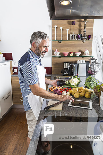 Austria  Man in kitchen with digital tablet preparing food