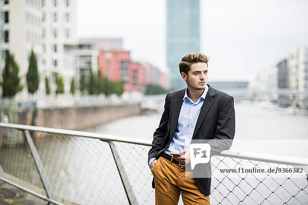 Deutschland  Hessen  Frankfurt  Portrait eines jungen Geschäftsmannes auf einer Brücke stehend