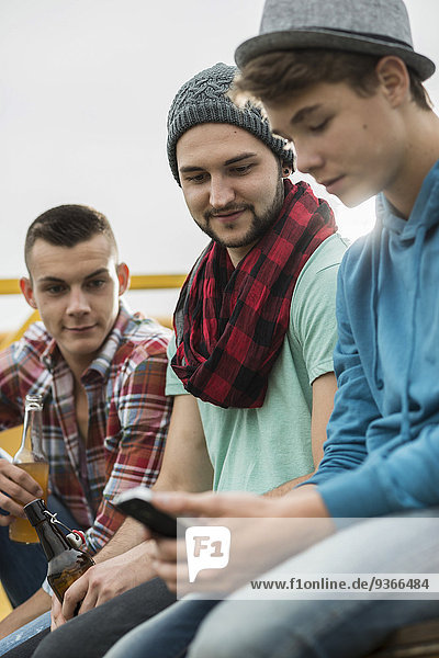 Gruppe von Freunden mit Handy auf Pick-up-Truck