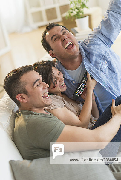 Hispanic friends cheering at television in living room