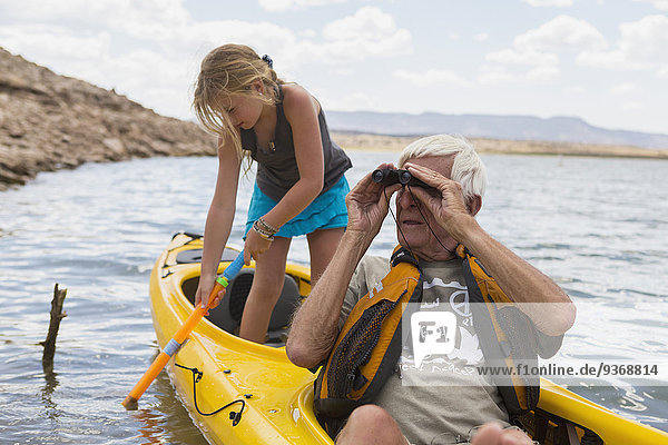 Older Caucasian man in kayak with granddaughter