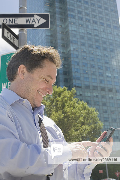 Hispanic businessman using cell phone on city street