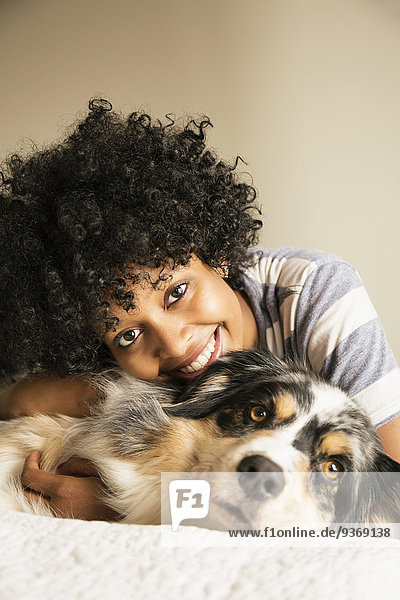 Mixed race woman laying with dog in bed