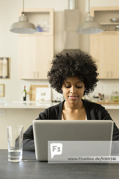 Mixed race woman using laptop at breakfast table