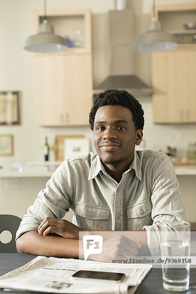 Black man reading newspaper at breakfast table
