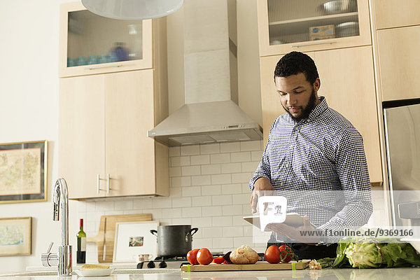 Mixed race man cooking with tablet computer in kitchen