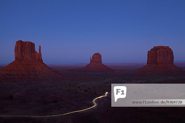 Long exposure of car driving past butte rock formations in desert landscape  Monument Valley Tribal Park  Utah  United States