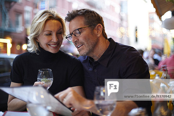 Caucasian couple reading menu at urban cafe  New York City  New York  United States