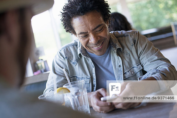 A man checking his smart phone at a diner table.
