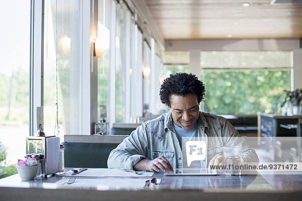 Ein Mann sitzt in einem Diner und benutzt ein digitales Tablett.