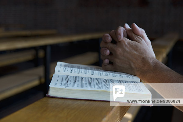 Betende Hände auf einem Gesangbuch in der Kirche