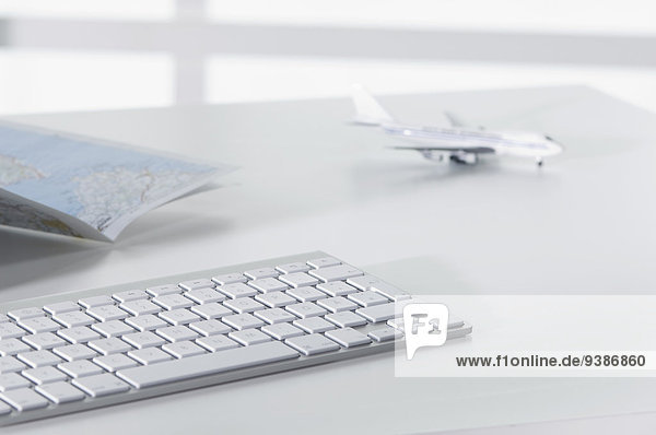 Flugzeugmodell  Tastatur und Landkarte auf Schreibtisch