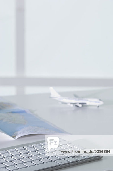 Flugzeugmodell,  Tastatur und Landkarte auf Schreibtisch