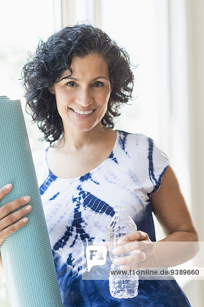 Portrait of smiling woman with yoga mat