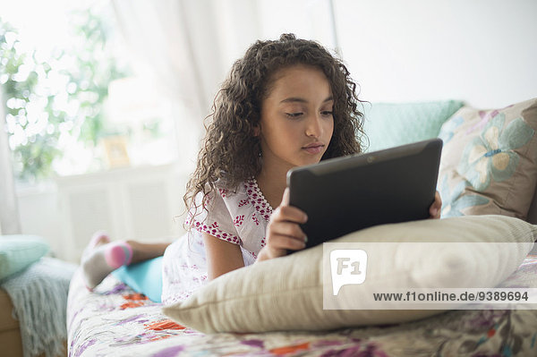Girl (8-9) using digital tablet on bed