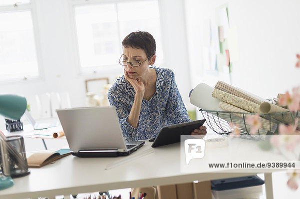 Senior business woman using laptop and tablet in office