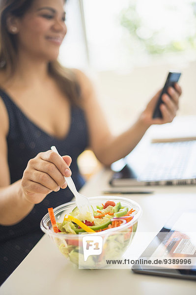 Handy benutzen Frau Salat Büro Kurznachricht essen essend isst
