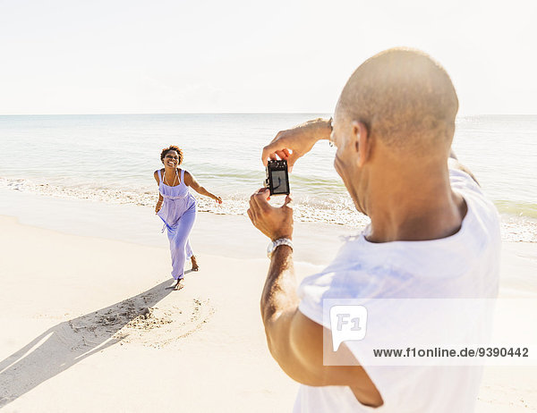 Man photographing woman on beach