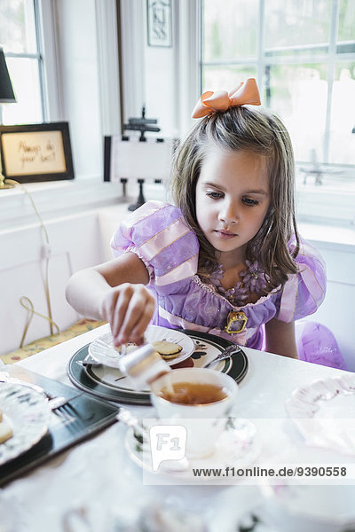 Girl (4-5) eating cookies at dining table