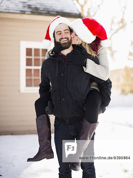 Portrait of young couple in santa hats  piggyback