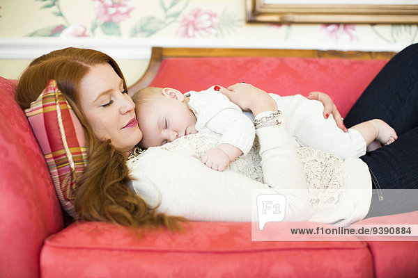 Mid adult woman napping with her baby boy (2-5 months)