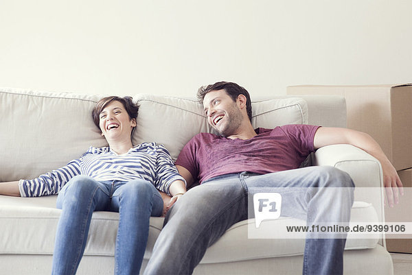 Couple relaxing on sofa while moving house