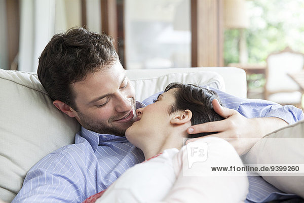Couple relaxing together on sofa  preparing to kiss