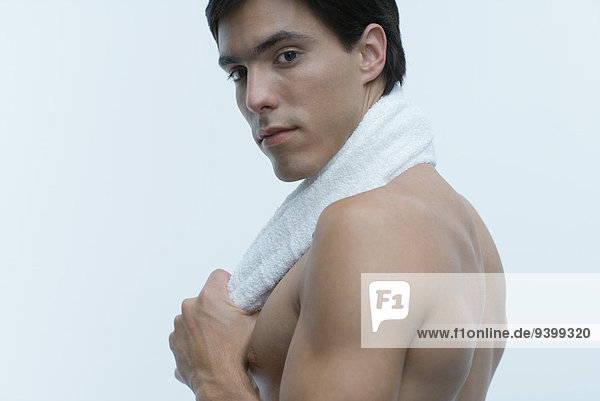 Barechested Mann mit Handtuch um den Hals  Blick über die Schulter auf die Kamera